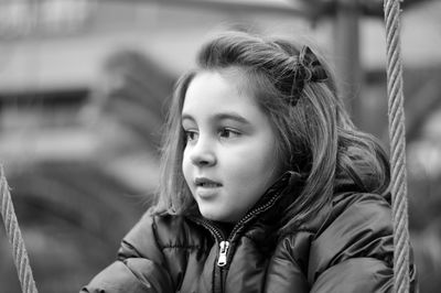 Cute girl looking away by ropes in playground