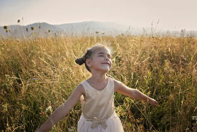 Happy girl standing on field against sky