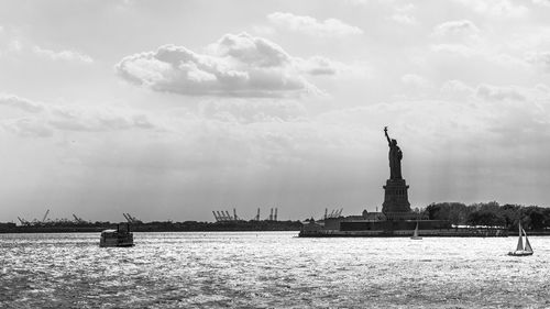 Statue in sea against cloudy sky