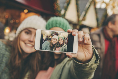 Two happy women taking a selfie on the christmas market