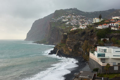 Scenic view of sea by buildings against sky