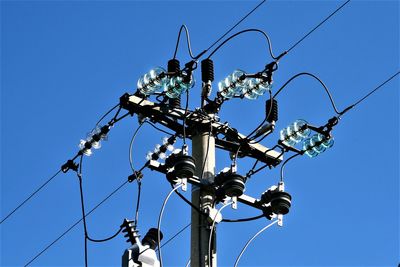 Concrete and steel pole with electrical cables, against the blue sky background.