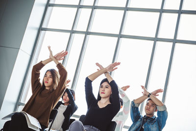 Low angle view of women standing against window