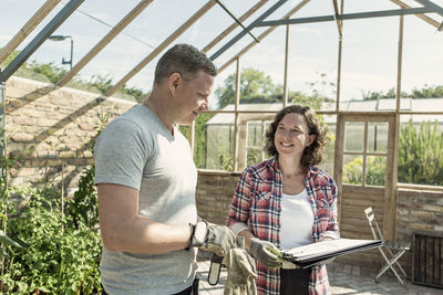 Happy woman discussing plan with man in greenhouse