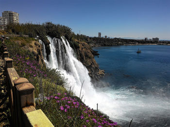 Scenic view of waterfall against clear blue sky