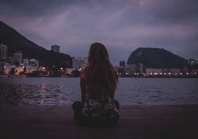 Rear view of woman looking at cityscape against sky