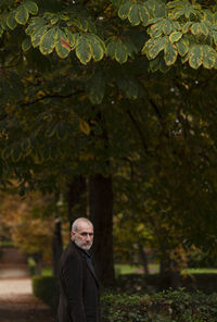 Portrait of adult man  in public park in autumn against green plants. shot in retiro park, madrid.