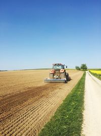 Tractor plowing field against clear sky in hochfelden