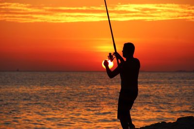 Silhouette of man fishing in sea