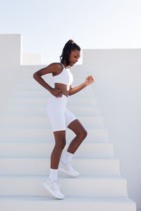 Full length of woman exercising against white background