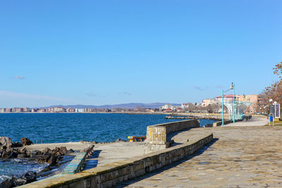 Pier over sea against clear blue sky