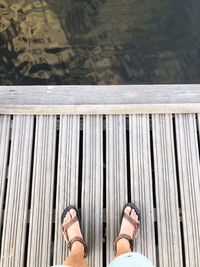 Low section of man standing on pier over river