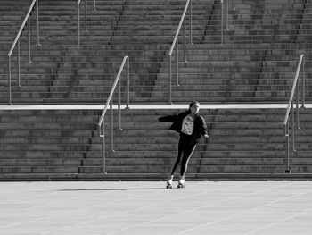 Rear view of woman running on footpath against wall