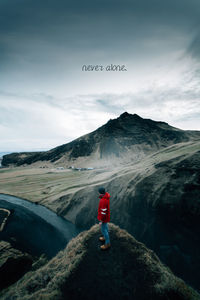 Man standing on rock against sky