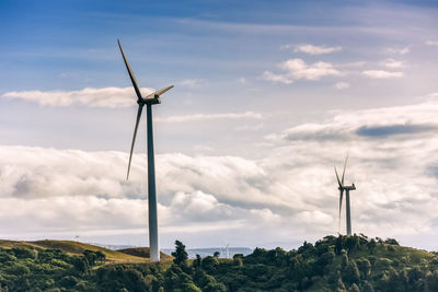 Wind turbines on land against sky