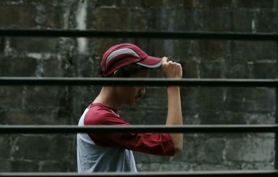 Side view of man wearing cap seen through security bars