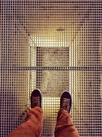 Low section of man standing on metal grate