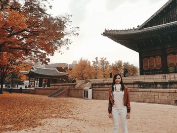 Portrait of woman standing against temple during autumn