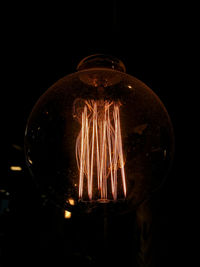 Close-up of illuminated light bulb against black background
