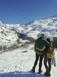 People on snow covered landscape against clear sky