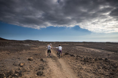 Rear view of men walking on landscape against sky