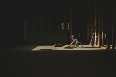 Baby boy with cleaning equipment standing in abandoned darkroom