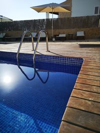 Empty chairs by swimming pool against sky