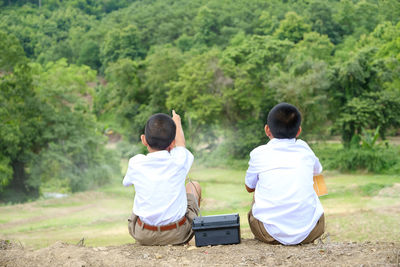 Rear view of friends sitting on field