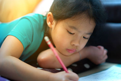 Close-up of cute girl writing in book on table