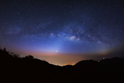Scenic view of silhouetted mountains against star field