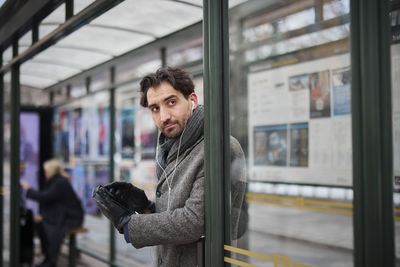 Elegant man with smartphone waiting on bus stop