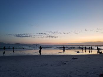 Silhouette people on beach against sky during sunset