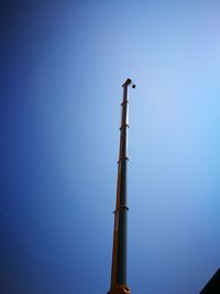Low angle view of birds perching on lamp post against clear blue sky