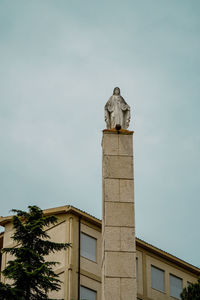 Low angle view of statue against building against sky