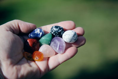 Cropped hand of person holding colorful stones