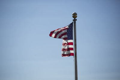 Low angle view of american flag waving against clear blue sky