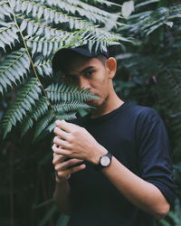 Portrait of young man holding leaves