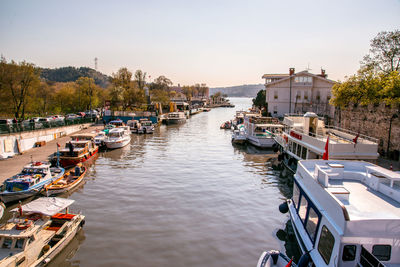 Boats moored in river against sky in city