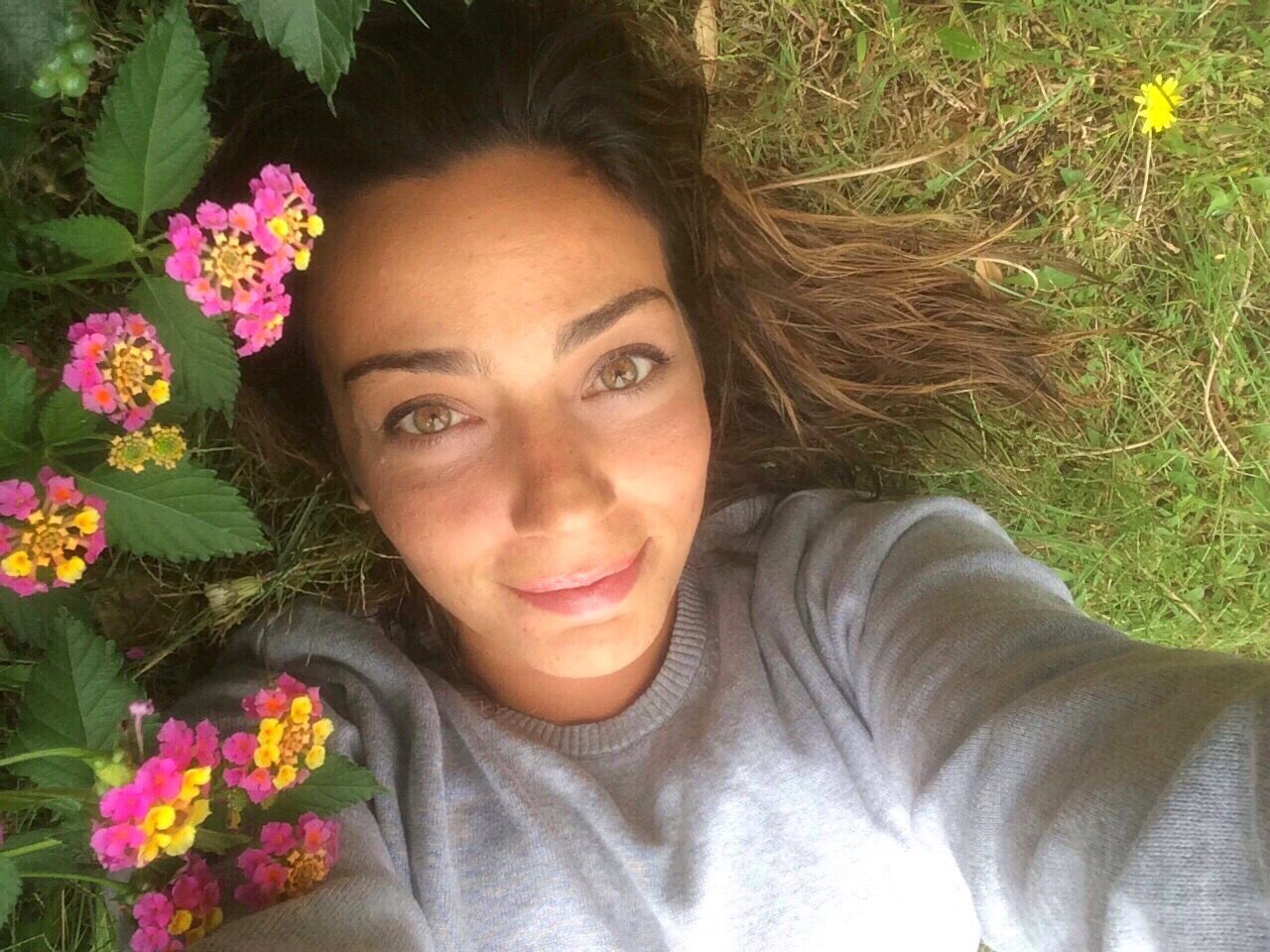 PORTRAIT OF SMILING WOMAN LYING DOWN IN FLOWER PLANT