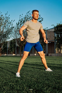 Portrait of young woman exercising on field