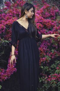 Beautiful woman standing by pink flowering plants