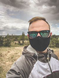 Portrait of man wearing sunglasses on field against sky