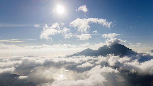 Low angle view of sunlight streaming through clouds