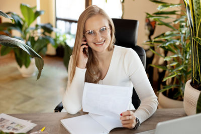 Portrait of a young business woman talking on the phone and looking through documents. business