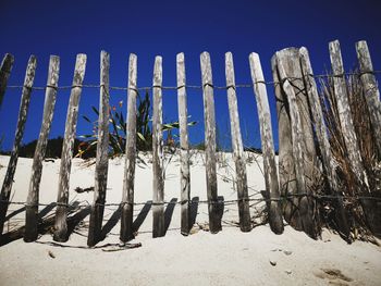 Wooden fence on snow covered land against sky