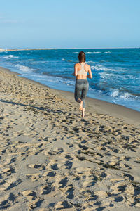 Full length rear view of man on beach against sky