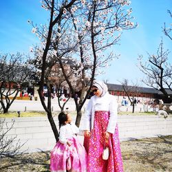 People by tree against sky