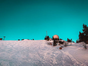 People on snow covered land against clear blue sky
