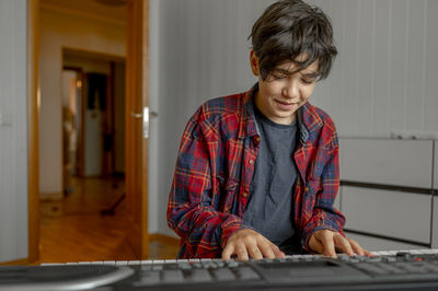 Smiling boy learning synthesizer at home