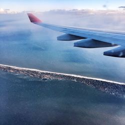 Airplane flying over sea against sky